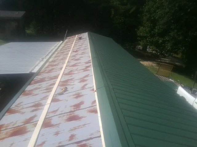 Old rusted panels beside newly installed green metal roofing in Greenacres