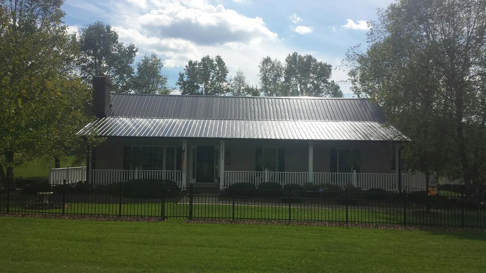Gray metal roof on a brick ranch with a full width front porch — Gutter Guard Installation work by our crew in Greenacres