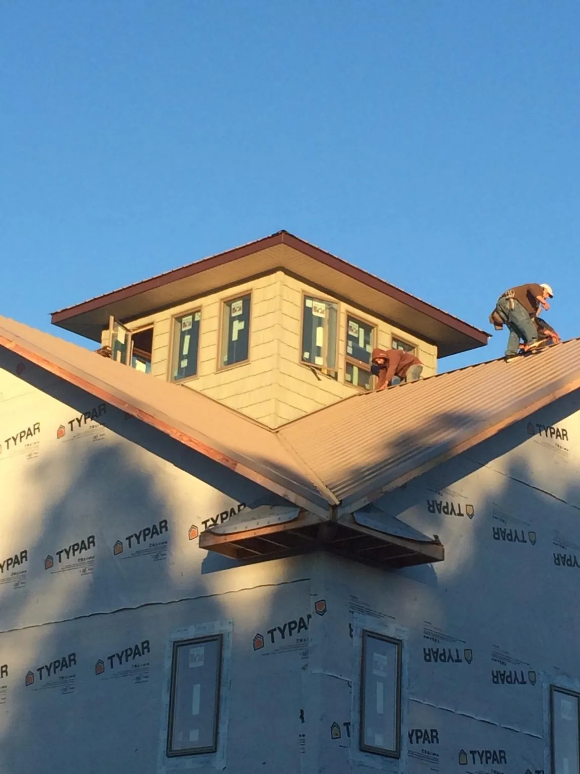 Roofers working around a rooftop cupola on a new metal roof at sunset — Roof Waterproofing in Greenacres by Roofing Brothers